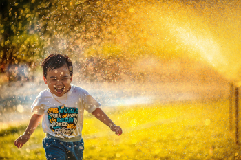 A toddler playing in a sprinkler