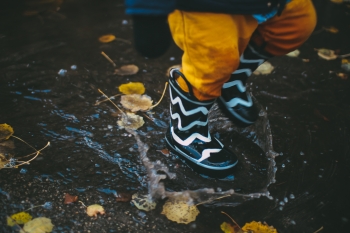 A child with boots running  in a puddle